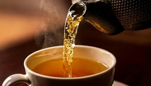 AI-generated close-up image showing a teapot from which tea is poured into a cup, AI generated