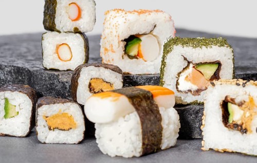 Various sushi dishes on dark grey stone surface