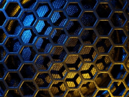Full frame colourful illuminated detail of a metallic grid in front of a loudspeaker