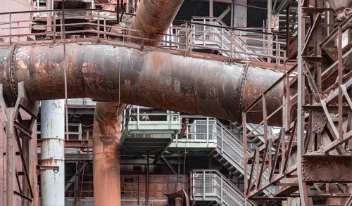 Weathered rundown industrial scenery with old corroded steel girders, stairs and metal tubes