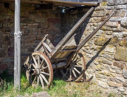 Medieval wooden cart at a stone wall in sunny ambiance