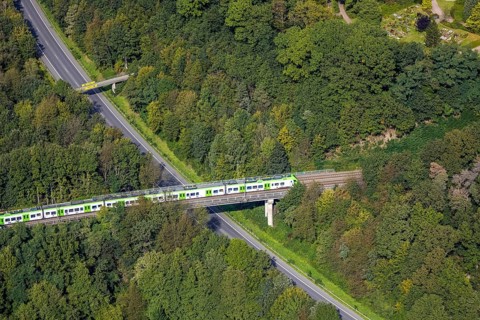 Aerial view, suburban railway crossing a bridge and adjacent pedestrian bridge over the