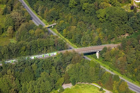 Aerial view, suburban railway crossing a bridge and adjacent pedestrian bridge over the