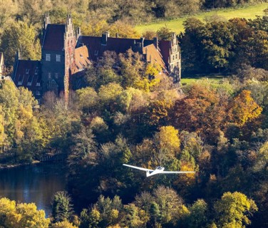 Aerial photo, motor glider at Heessen Castle in the autumnal forest in the Heessen district of