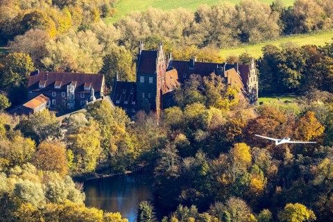 Aerial photo, motor glider at Heessen Castle in the autumnal forest in the Heessen district of