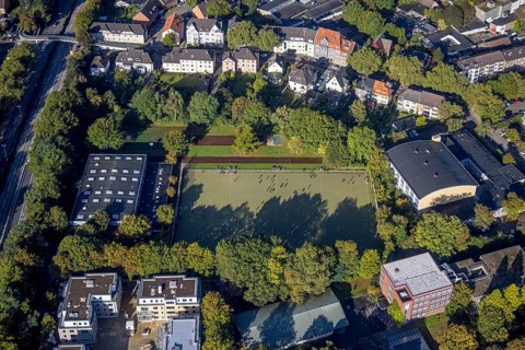 Aerial view, indoor swimming pool and sports hall as well as youths on the sports field at the