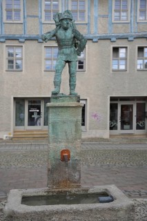 Wood carrier by Bernhard Frydag, 1914, male figure carrying basket with wood on his back, symbol