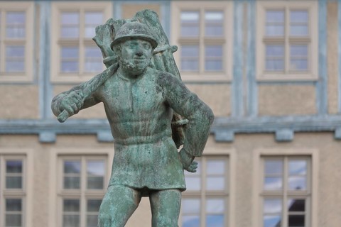Wood carrier by Bernhard Frydag, 1914, male figure carrying basket with wood on his back, symbol
