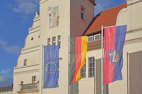 Renaissance town hall with EU flag, German national flag and town flag, three, flags, sundial, wall