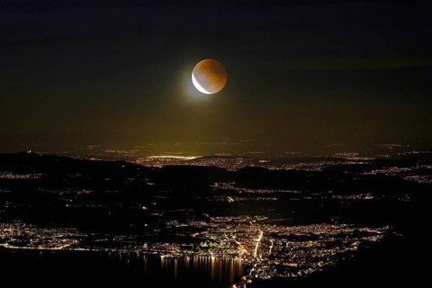 Blood moon, total lunar eclipse over the illuminated city and Lake Zug, Zug, Canton Zug,
