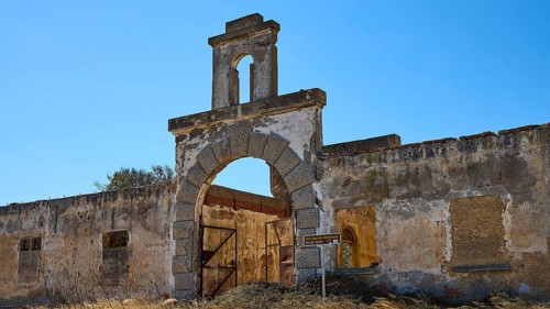 Dilapidated archway of an old factory, surrounded by crumbling walls under a clear sky, Old silk
