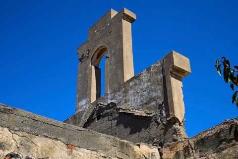 Tower-like structure with crumbling façade in front of a clear blue sky, Old Silk Factory, German