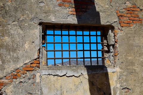 Barred window with shadows on old, rustic brick walls, Old silk factory, Military prison of the