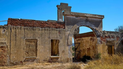 Faded walls with a central archway surrounded by wild vegetation, Old Silk Factory, German