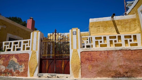 A yellow rustic building with a metallic Tor tor under a blue sky, Kattavia village, southern tip