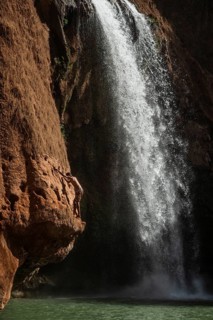 A Moroccan young man climbs the rock before jump from into the water under a waterfall Ouzoud