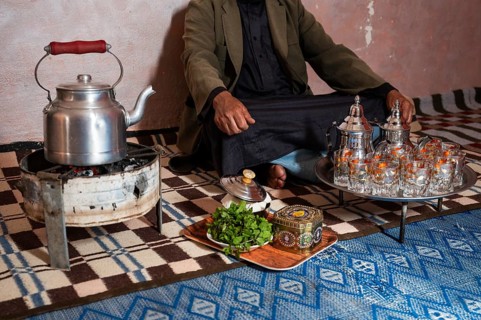 Moroccan man in front of the tea set with the kettle and glasses