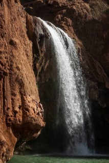 A Moroccan young man climbs the rock before jump from into the water under a waterfall Ouzoud