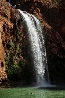 Relaxed woman floats on his back under beautiful Ouzoud waterffall in Morocco
