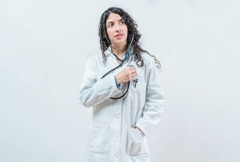 Doctor listening to her heart with stethoscope, isolated. Female doctor with stethoscope on her