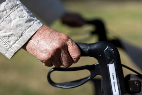 Close-up of wrinkled hands of a 90+ year old senior citizen in the park of a retirement home,