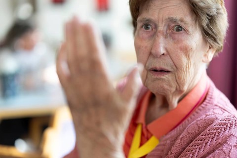 Over 90-year-old senior citizen with dementia talks and gesticulates with her wrinkled hands in a