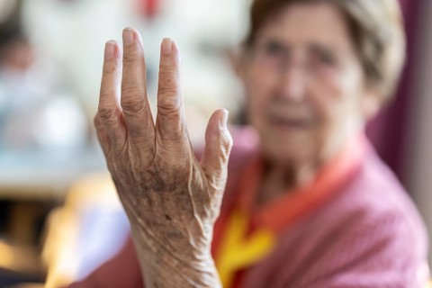 Over 90-year-old senior citizen with dementia talks and gesticulates with her wrinkled hands in a