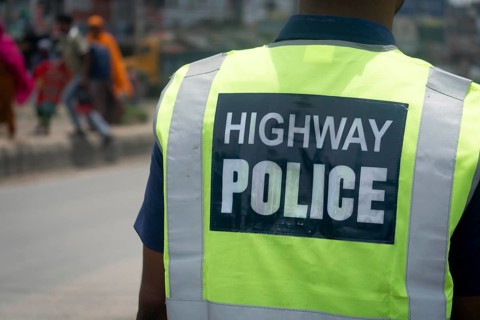 Highway police officer on duty viewed from the back with a reflective vest, Dhaka, Bangladesh