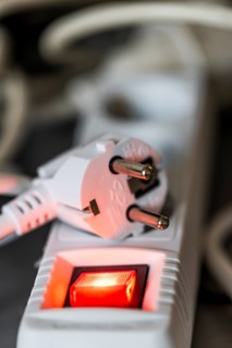 Close-up of a white power plug, Schuko plug, on a multiple socket with red indicator light,