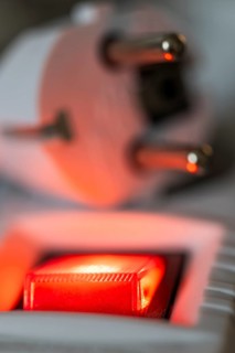 Close-up of a white power plug, Schuko plug, on a multiple socket with red indicator light,