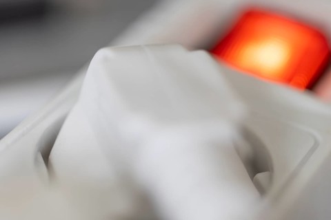 Close-up of a white power plug, Schuko plug, plugged into a multiple socket with red indicator