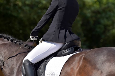 Close-up of horse's back, saddle and rider's seat during a dressage test at a horse show,