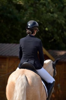 Close-up of horse and rider with equipment from behind during a dressage competition at a horse