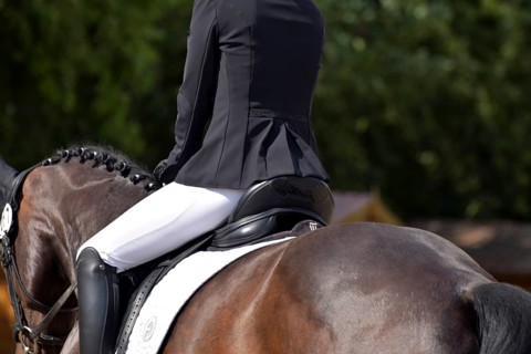 Close-up of horse's back, saddle and rider's seat during a dressage test at a horse show,