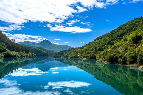 The tranquil waters of ibiur reservoir mirror the vibrant blue sky and fluffy white clouds,