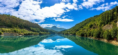 The serene ibiur reservoir mirrors the sky and surrounding hills, creating a tranquil panorama of
