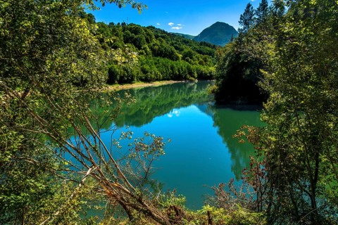 Ibiur reservoir is reflecting the surrounding lush vegetation and blue sky on a beautiful sunny day