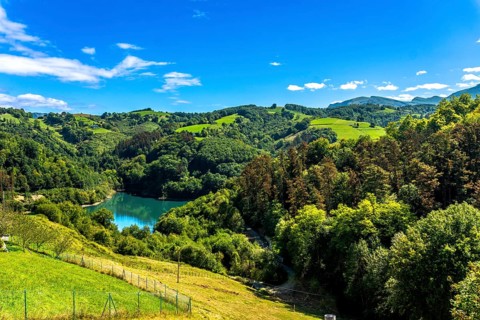Ibiur reservoir reflects the vibrant blue sky amidst the rolling green hills and lush forests of