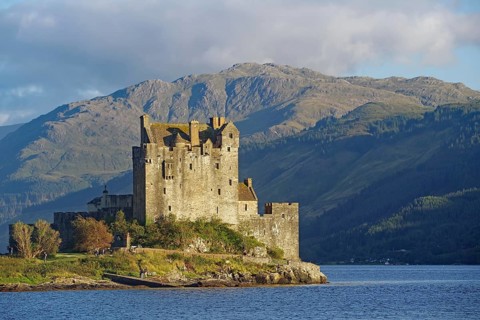 Historic castle on an inlet with dramatic mountains in the background, Eilean Donan Castle,