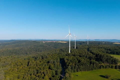 Three wind turbines rise above lush forest and green countryside, near Schorndorf, Rems Valley,