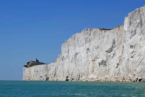 Wide cliff landscape with a small lighthouse under a blue sky. Old Harrys Rock, Bournemouth,