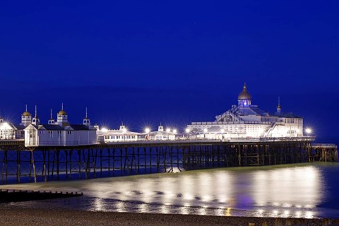 Illuminated pier at night with reflecting lights in the water, Victorian, Bournemouth, England,