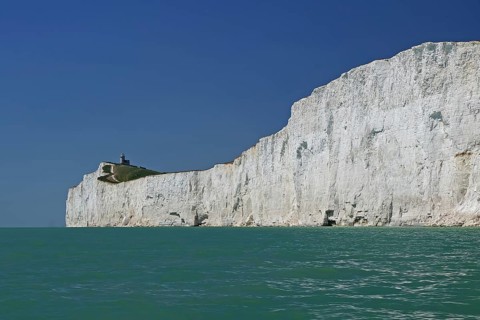 White cliffs with a small lighthouse by the turquoise sea, Old Harrys Rock, Bournemouth, Dorset,