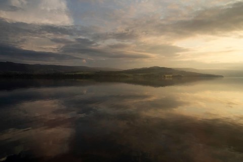 The sky and clouds are reflected on the surface of Lake Mjøsa or Mjosa just in front of sunset,