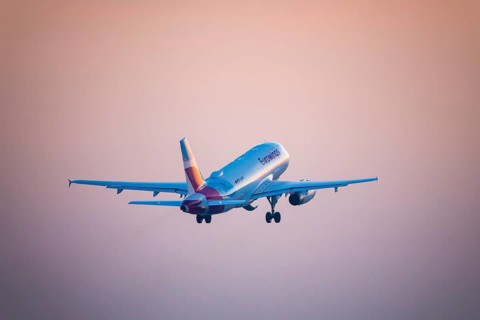A Eurowings aeroplane takes off and disappears into an orange evening sky, Stuttgart,