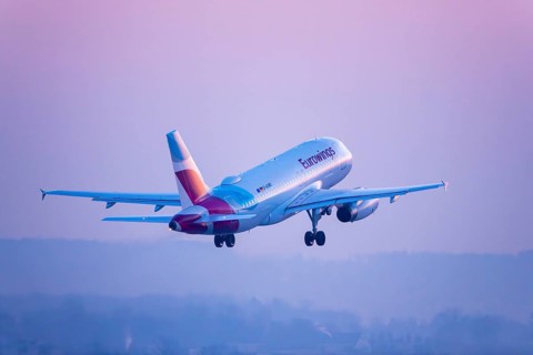 A Eurowings aircraft soars in a pink-coloured sky, Stuttgart, Baden-Württembwerg, Germany