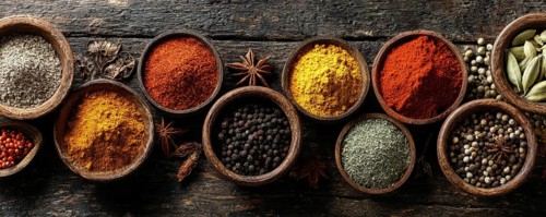 Different spices in bowls on table on rustic dark wooden background. Indian colorful spices for