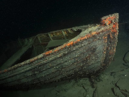 Wreck of a rowing boat lies on the sandy lake bottom in the dark water, dive site Schoggiwand, Lake