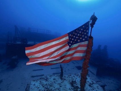 USA flag on a wreck under water, surrounded by deep blue. Dive site Wreck of the USS Spiegel Grove,
