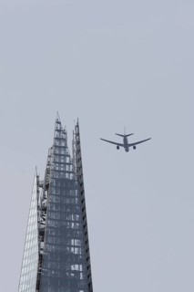 Jet passenger aircraft in flight over The Shard skyscraper building, London, England, United